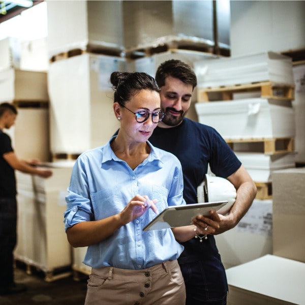 Warehouse employees using a tablet for inventory or sales order management in a logistics environment