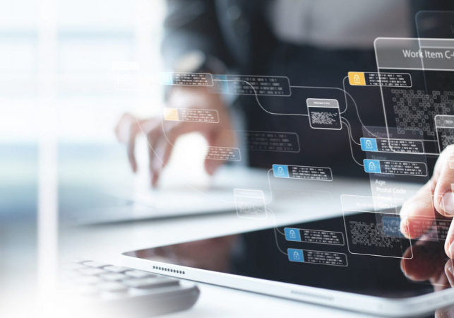 Fingers interacting with a digital tablet displaying abstract holographic data flowcharts