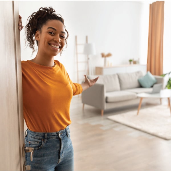 Smiling woman opening her apartment door, welcoming a guest or inspector