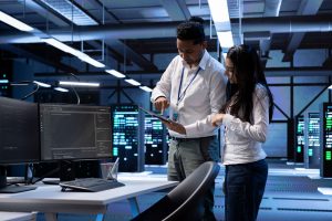 Two people in a data center discuss information on a tablet.