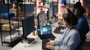 Office scene with three people wearing headsets, working at desks with computers.